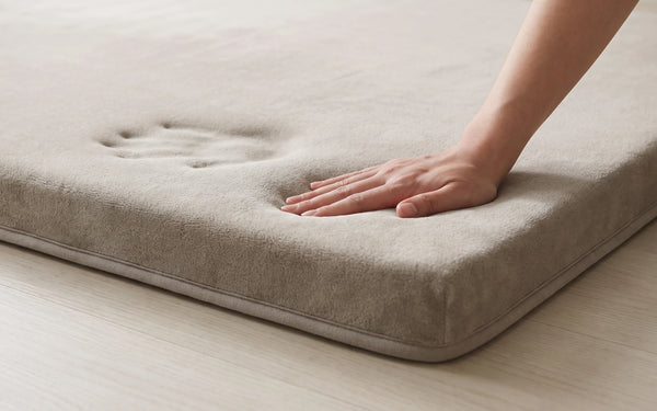 An adult palm pressing into the mat with the rebound dent still visible